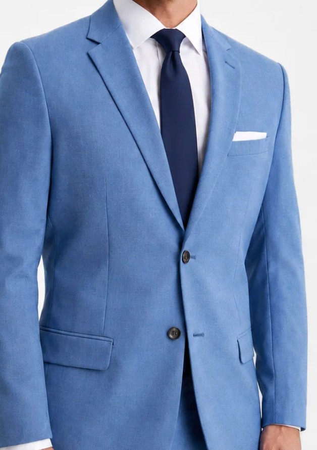 A man wearing a light blue suit jacket with a white dress shirt, navy tie, and white pocket square, shown from the chest down against a plain white background.
