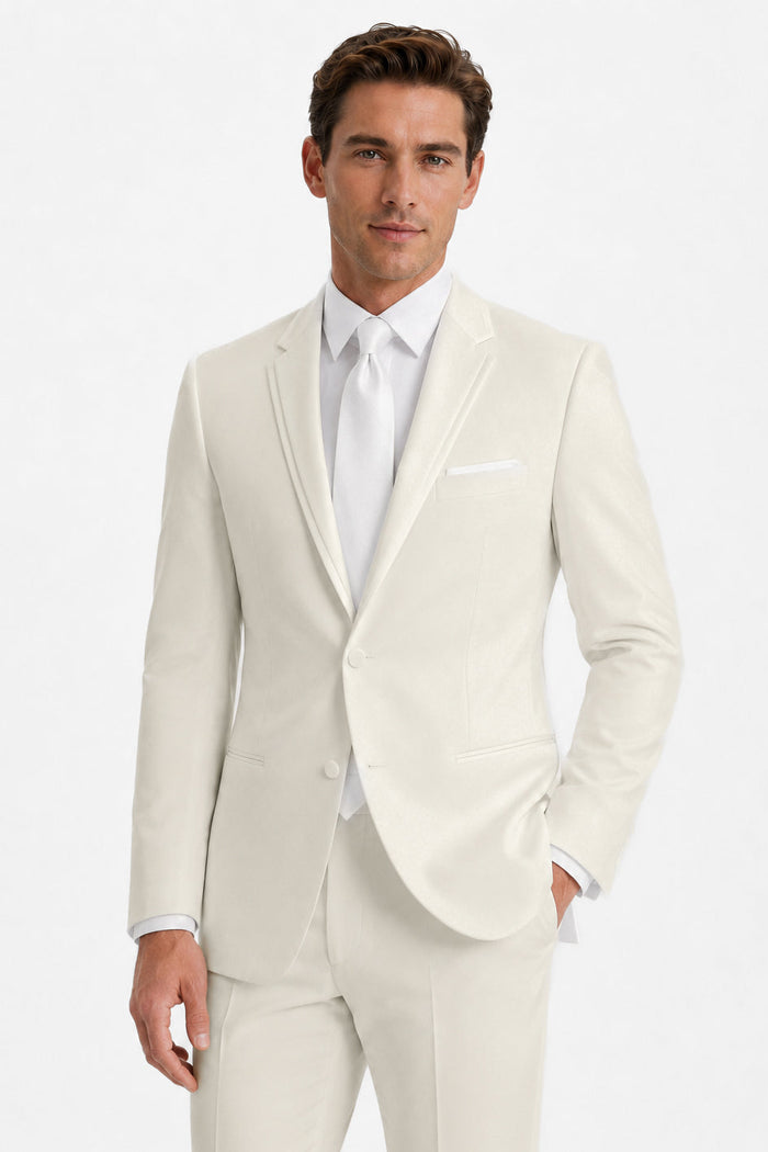 A man modeling a light cream or off-white suit with a white dress shirt and white tie against a plain white studio background.