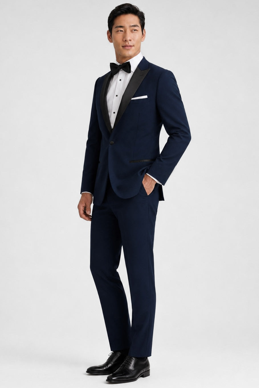 Man wearing a navy tuxedo with a bow tie on a white background